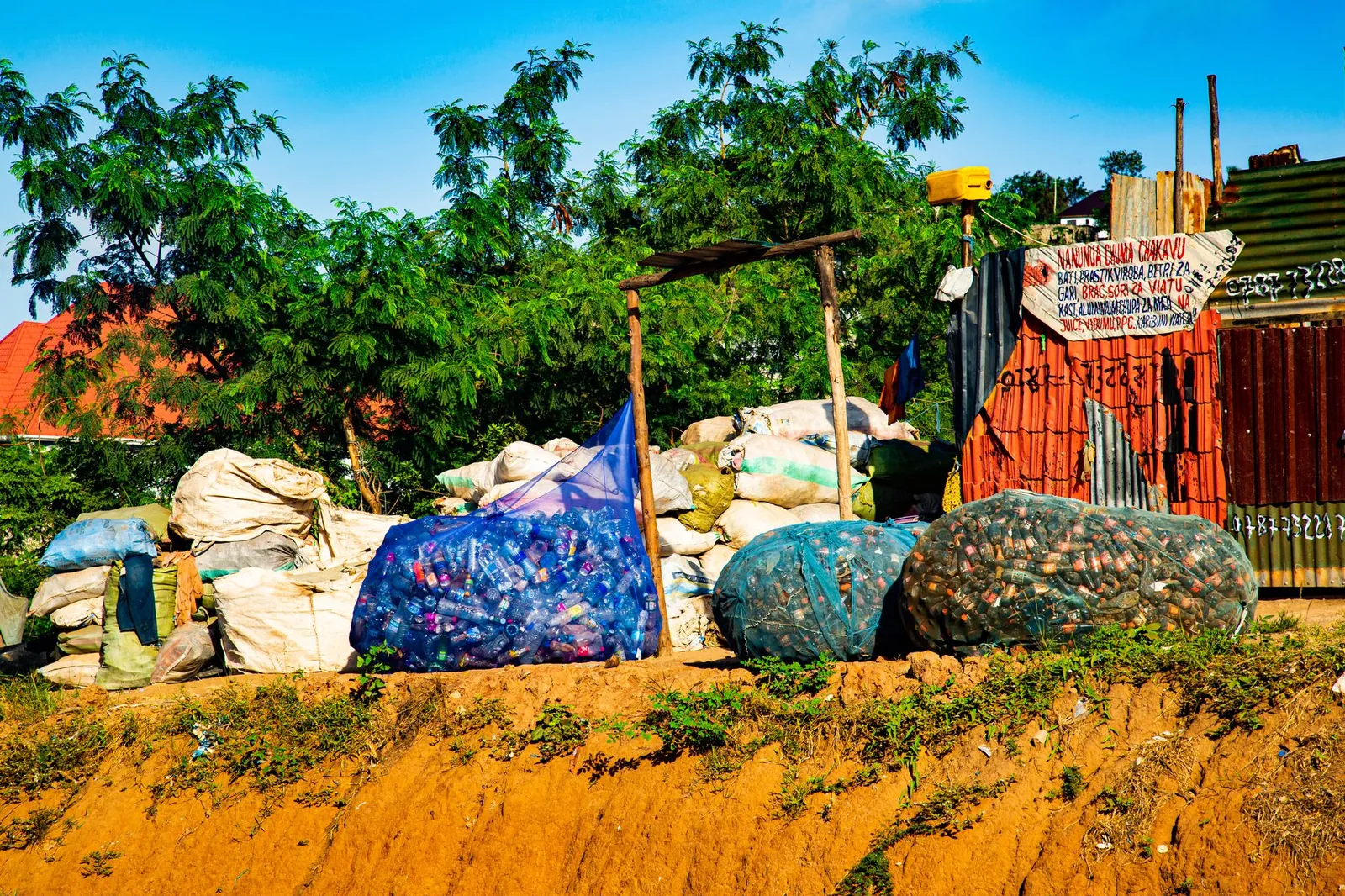 A community collection point in Dar es Salaam, Tanzania, with bagged plastic bottles ready for aggregation